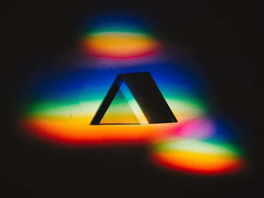 Glass prism on a dark surface splitting light into a rainbow of colors