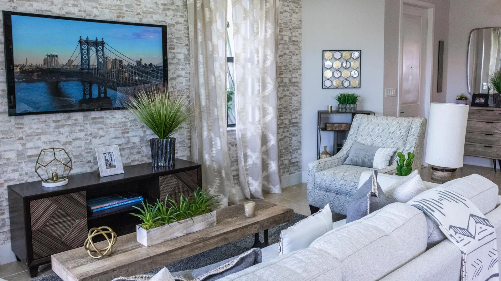 Bright modern living room with a wall-mounted TV showing a colorful photo of a city bridge at dusk